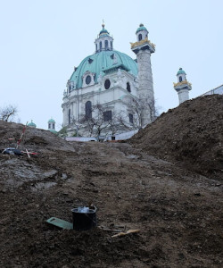 Photo of the Karlskirche (St. Charles Church) in Vienna, shot upwards from below ground level, heaps of dirt and some tools on the ground indicate that excavation works are in progress