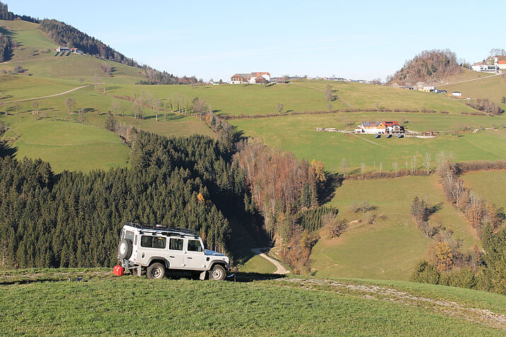 Truck with technical equipment parked on the road, mountains and houses in the background