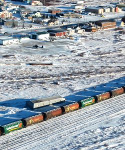 Image showing a freight train as it crosses a snowy landscape, houses in the background