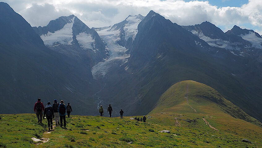 Group of wanderers hiking along a mountain ridge, snowy peaks in the background