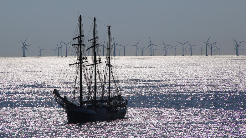 Open sea, a ship and a large wind park in the background