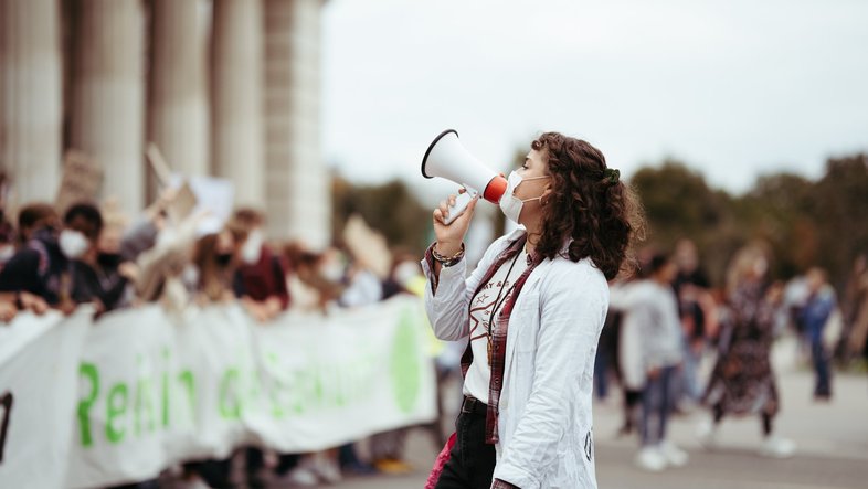 Photo of a Fridays for Future protest, a young woman with a megaphone in the foreground