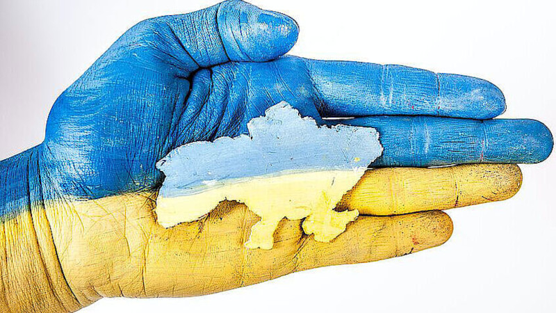 Image showing a hand holding the outline of Ukraine, coloured in the Ukraine's national colours blue and yellow
